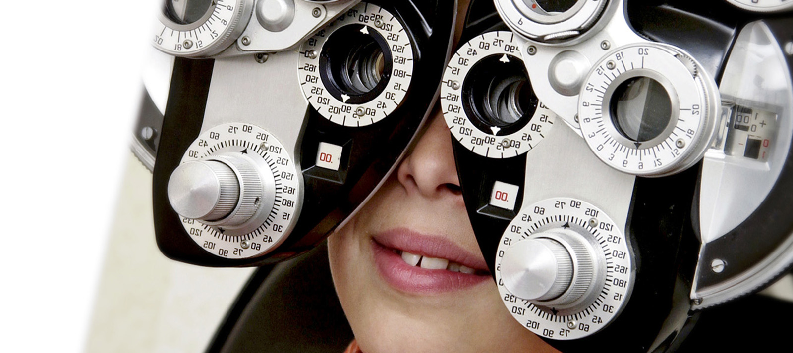 The image shows a person wearing an eye patch over their right eye, looking through a pair of binoculars with both eyes, while seated in front of a large magnifying glass.