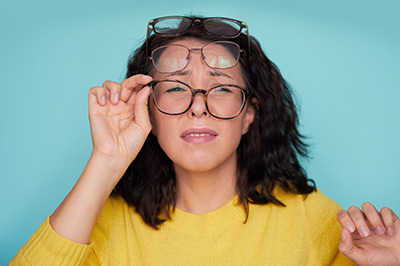 The image features a woman with glasses and a surprised expression, holding her hands up to her face, against a blue background.