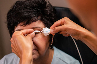 An elderly woman receiving eye care assistance with an eyepiece.