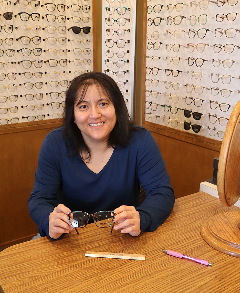 A woman holding a pair of glasses at an optical store.