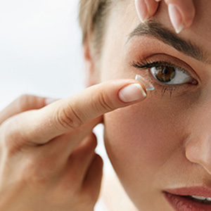 A woman applying blue eye shadow with a brush.