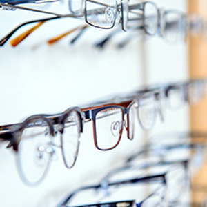 The image shows a display of eyeglasses on shelves, with various styles and designs visible.