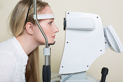 A woman using an eye machine with an adjustable headrest.