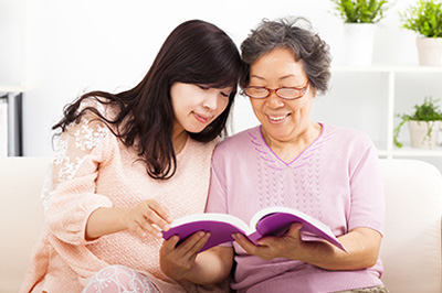 The image depicts two individuals engaged with an open book, suggesting a reading or learning activity.